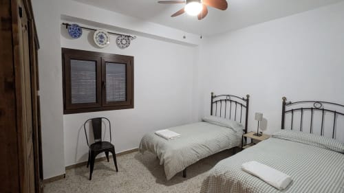 Dormitorio luminoso con dos camas individuales de estructura metálica y ropa de cama a cuadros verdes en la villa Casa Rural Ribera del Hueznar de Constantina, Cazalla de la Sierra