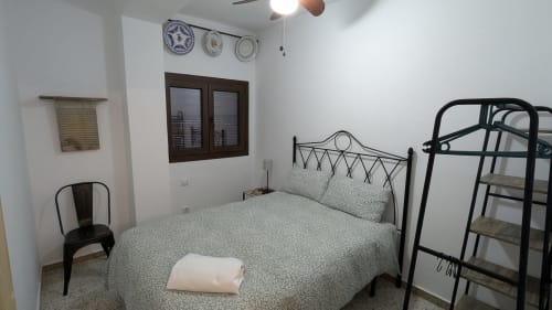 Dormitorio de la villa Casa Rural Ribera del Hueznar en  Constantina, Cazalla de la Sierra con cama de estructura metálica, ropa de cama verde y platos decorativos