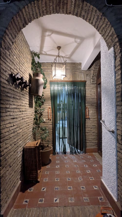 Encantador acceso a la villa Casa Rural Ribera del Hueznar en Constantina, Cazalla de la Sierra con arco de ladrillo, linterna colgante y azulejo decorativo