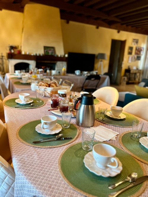 Table de petit-déjeuner élégante à La Maison de la Colline, B&B à Vers en France, avec sets de table verts et tasses blanches