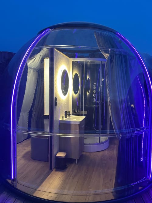 Bulle transparente avec éclairage néon violet, salle de bain moderne et bain à remous privé à l'hôtel Bubble Jade à Bazouges la