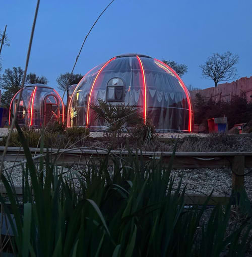 Dôme transparent Bubble Jade avec éclairage rouge néon et bain à remous privé dans le jardin au crépuscule, Bazouges-la-Pérouse