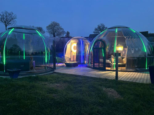 Chambres bulles transparentes illuminées avec bordures néon vert au crépuscule, Bubble Jade à Bazouges la Pérouse, France