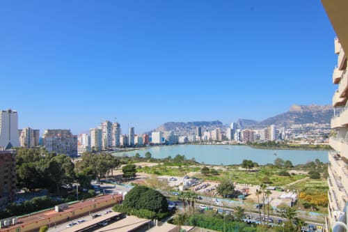 Balcony view of Calpe's turquoise bay, beach, and Mediterranean coastline with mountains and high-rise buildings