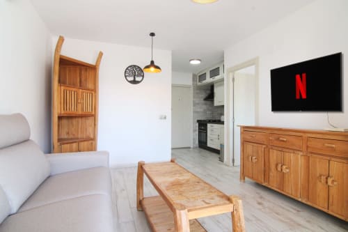 Bright Calpe apartment living room with TV, wooden furniture, kitchen access, and modern amenities