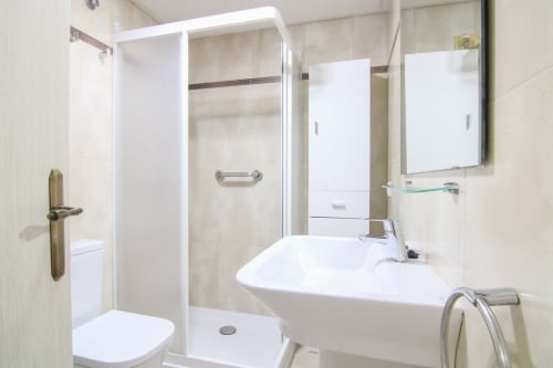 Modern bathroom with walk-in shower, white sink, and mirror at Riurau Home apartment in Calpe