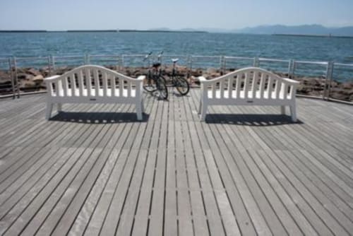 Pontile in legno con panchine bianche sul mare, bicicletta parcheggiata, alloggi lungomare di Cagliari