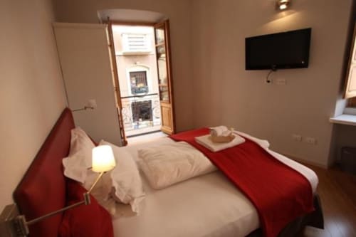 Camera moderna presso l'Affittacamere Numero3 a Cagliari con letto matrimoniale, accenti rossi, TV a schermo piatto e accesso al balcone