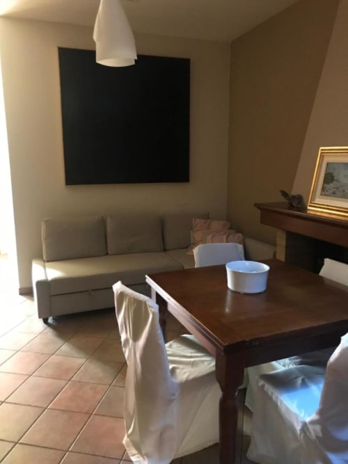 Sala comune di Affittacamere Numero3 a Cagliari con tavolo da pranzo, sedie, divano, schermo a parete e quadri incorniciati.