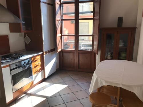 Luminosa zona cucina-pranzo presso l'Affittacamere Numero3 a Cagliari con mobili in legno, cucina a gas e porte verso la terrazza