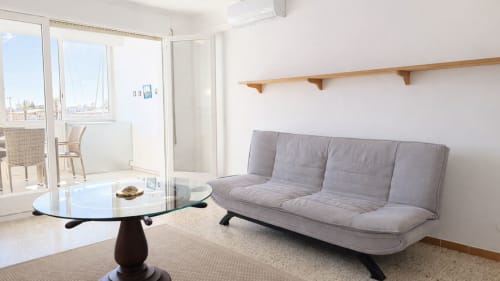 Sala de estar moderna en Holidays Costa Brava con sofá gris, mesa de cristal y vistas al canal en Empuriabrava