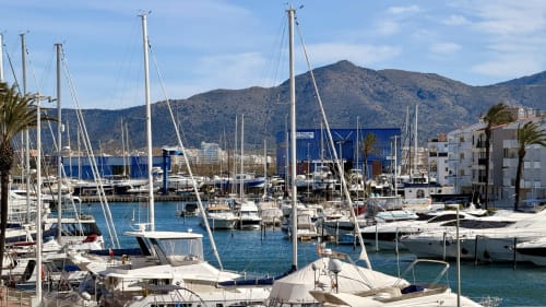 Marina de Empuriabrava con veleros blancos, aguas azules y montañas al fondo, Costa Brava
