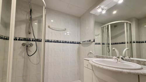 Baño moderno en el hotel Holidays Costa Brava de Empuriabrava con ducha, lavabo e iluminación en espejo