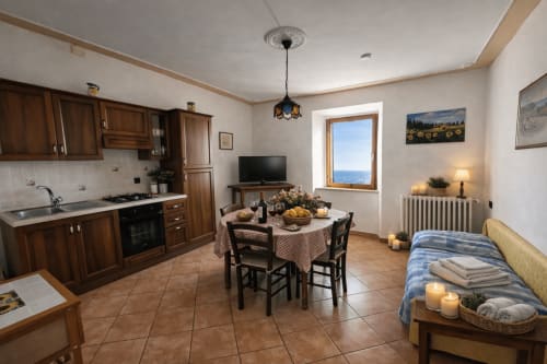 Cozy cottage apartment in Montecatini Val di Cecina with wooden kitchen, dining area, bed, and sea view through window