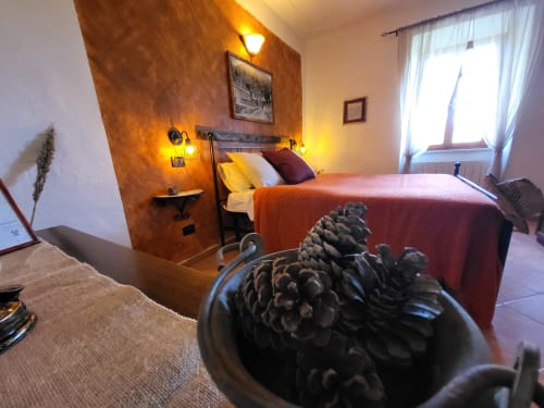 Camera accogliente presso I Castagnini B&B con parete arancione, letto matrimoniale, illuminazione soft e vista sul giardino a Montecatini Val di