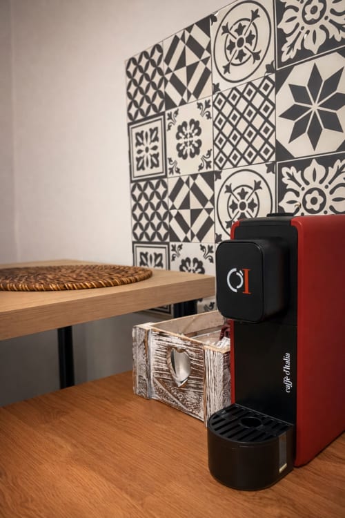 Modern coffee machine in SambaSStays Carioca apartment, Cataldo, with geometric patterned wall and wooden furniture.