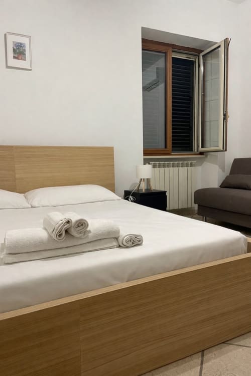 Modern bedroom at SambaSStays Carioca Monolocale in Cataldo with wooden bed, white linens, and city view window