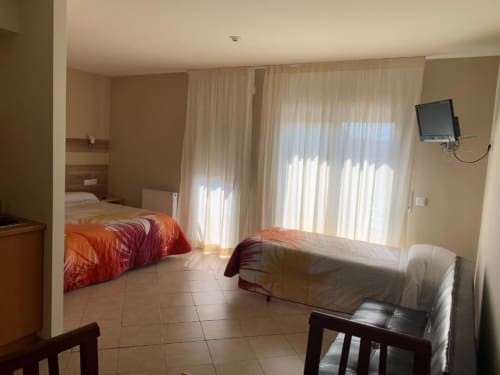 Espaciosa habitación de hotel en Turismo Rural Raquel con camas individuales, baldosas de barro cocido y luz natural desde puertas de cristal en Sant