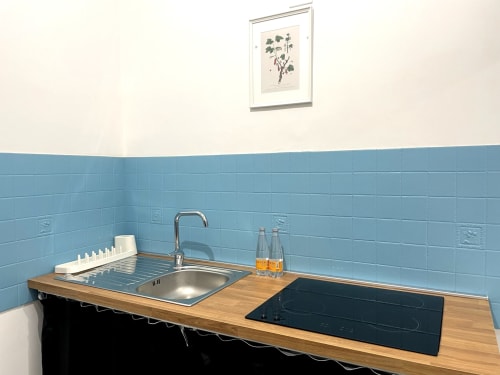Modern kitchenette in Carioca Bilocale apartment at SambaSStays with blue tile backsplash, wooden countertop, stove, sink and