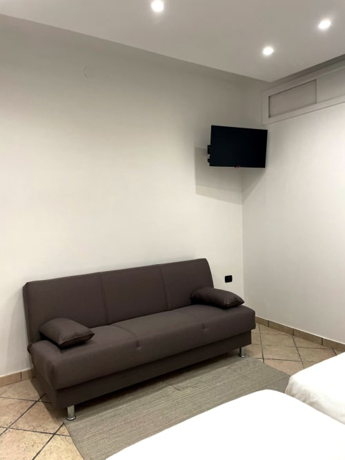 Modern living room in Carioca apartment at SambaSStays with dark sofa, mounted TV, and bright white walls in Cataldo, Italy