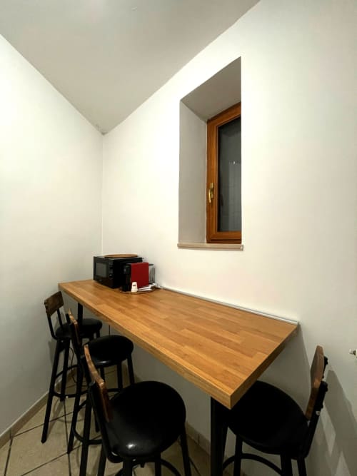 Compact dining area in Carioca Bilocale apartment at SambaSStays Cataldo with wooden table, bar seating, and window.