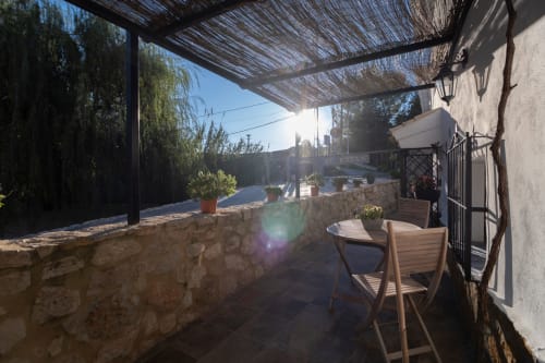 Terraza sombreada del Hotel Spa El Batán con sillas de madera y vistas al río en Castillo de Locubín