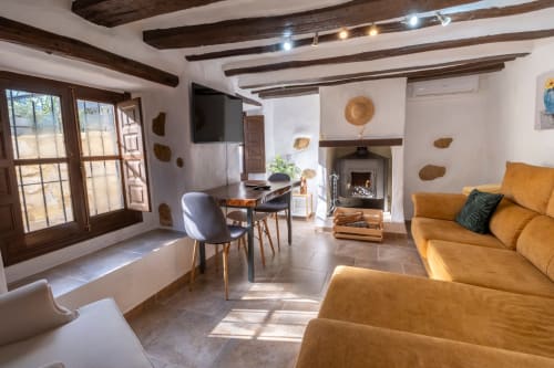 Sala de estar de Casita del Río 1 en El Batán Hotel Spa con sofá mostaza, chimenea y vigas de madera