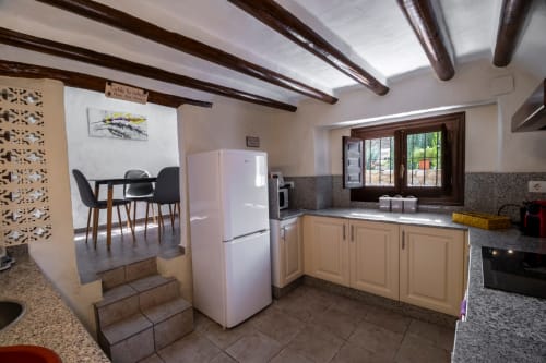 Cocina con vigas de madera, refrigerador blanco, armarios crema y comedor del Hotel Spa El Batán, Castillo de Locubín