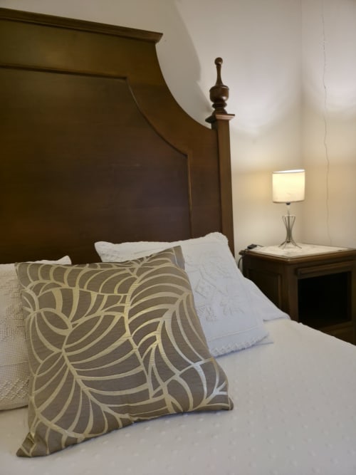 Quarto elegante do hotel Enjoy The North em Viana do Castelo com cama em madeira, almofadas estampadas e luminária de cabeceira