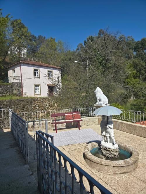 Pátio tranquilo do hotel Enjoy The North em Viana do Castelo com estátua branca, banco e arquitetura tradicional portuguesa