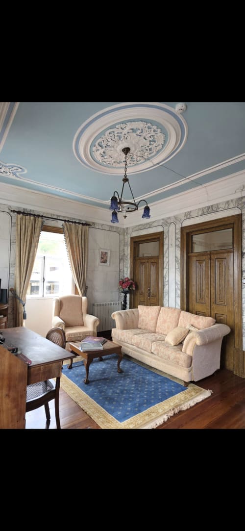 Elegante sala de estar no Enjoy The North, quarto Mesieiro, Viana do Castelo, com sofá creme, teto ornamentado e azul