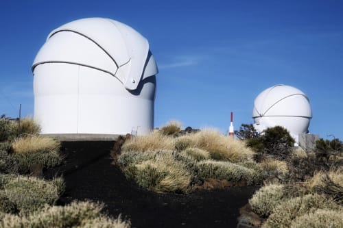 Observatory domes at Teide Observatory in Tenerife with desert vegetation and clear blue sky