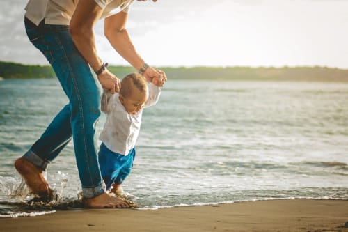 Parent and toddler wading in the sea at Costa Adeje beach, enjoying family vacation time