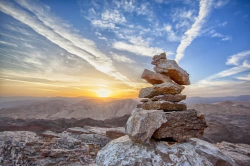 Stacked rocks at sunset overlooking Tenerife mountains, symbolizing balance and tranquility for Costa Adeje accommodation