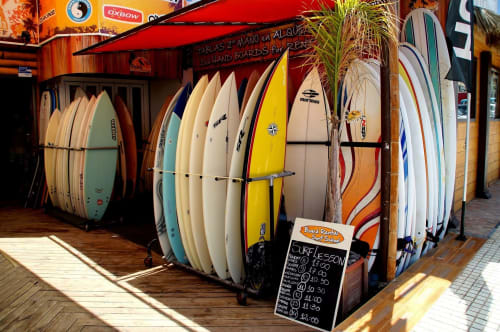 Surfboard rental shop display in Costa Adeje, Tenerife with colorful boards and pricing board