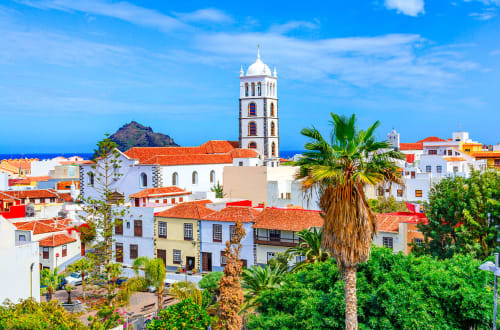 Colorful colonial buildings with palm trees in Costa Adeje, Tenerife, featuring white church with bell tower overlooking the