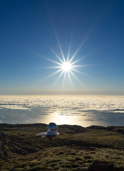 Observatory dome on volcanic hillside with bright sun and sea view in Tenerife, Spain