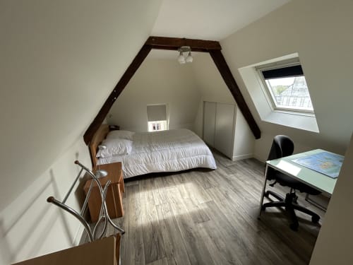 Chambre spacieuse à la mansarde chez Marie et Jean François à Dol de Bretagne avec lit à baldaquin, bureau et fenêtres de toit