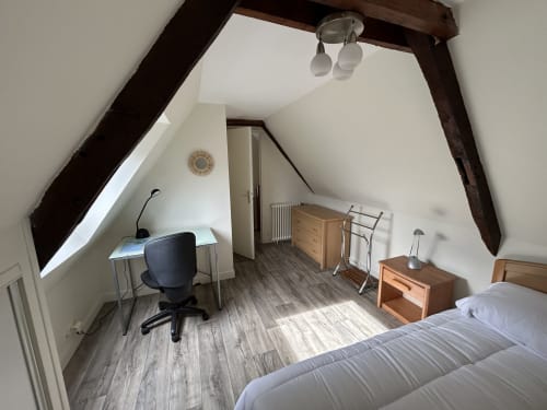 Spacieuse chambre mansardée Chez Marie Et Jean François à Dol de Bretagne avec poutres apparentes, bureau, mobilier bois et vue ville
