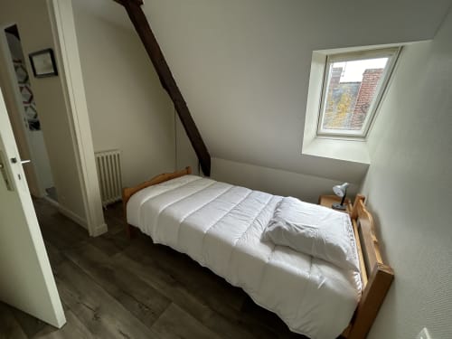 Chambre lumineuse avec lit blanc et cadre bois, lucarne et vue sur la ville à Chez Marie Et Jean François, Dol de Bretagne