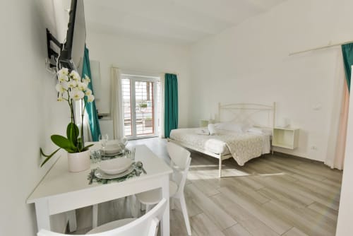 Camera moderna nell'appartamento di Varigotti con letto in metallo bianco, scrivania, balcone con vista sulla città e pavimenti in legno