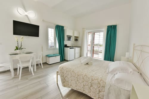 Camera da letto moderna a Varigotti con letto matrimoniale, vista mare, TV, angolo cottura e tende turchesi