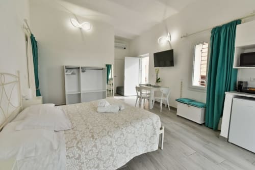 Camera moderna a Varigotti con vista mare, TV a schermo piatto, tende verdi e arredi contemporanei