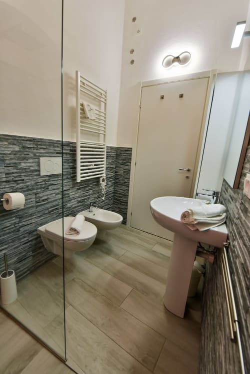 Bagno moderno nell'appartamento di Varigotti con bidet, wc, lavabo rosa su piedistallo, piastrelle a righe e doccia walk-in