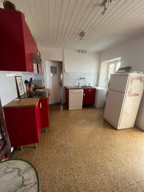 Cuisine aux armoires rouges, électroménagers blancs et murs carrelés de la villa Brando Altezza