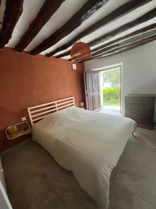 Chambre lumineuse avec mur en terre cuite, plafond à poutres blanches et vue sur mer à la villa Altezza à Brando
