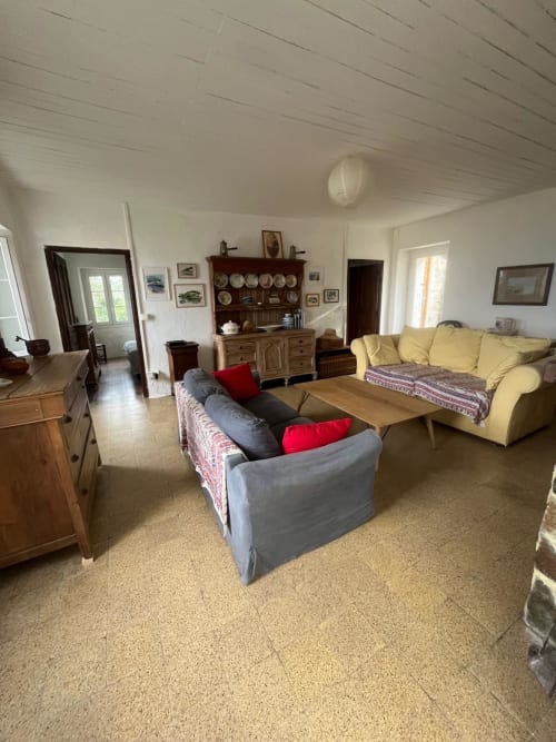 Spacieuse salle de séjour de la villa Brando avec canapé jaune, sièges gris, mobilier en bois et accès à vue sur plage