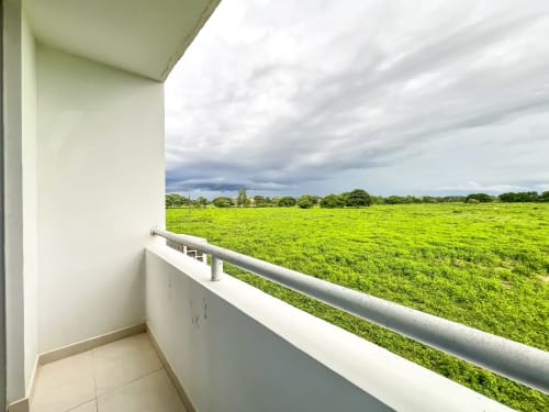 Vista del balcón en apartamento Olamar Living, Coveñas, con amplios campos verdes y cielo nublado