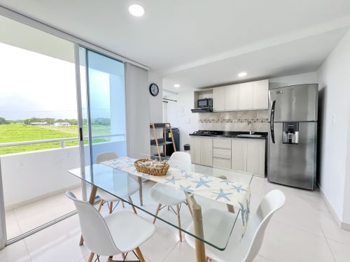 Moderna zona cocina-comedor en Olamar Living, Coveñas con electrodomésticos de acero inoxidable, gabinetes blancos y vistas panorámicas al lago