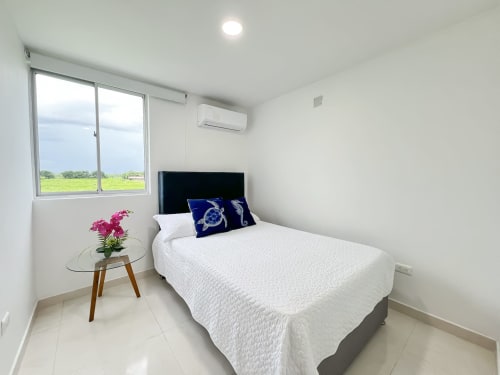 Habitación moderna en Olamar Living con cama matrimonial, vista al lago, aire acondicionado y decoración minimalista blanca en Coveñas